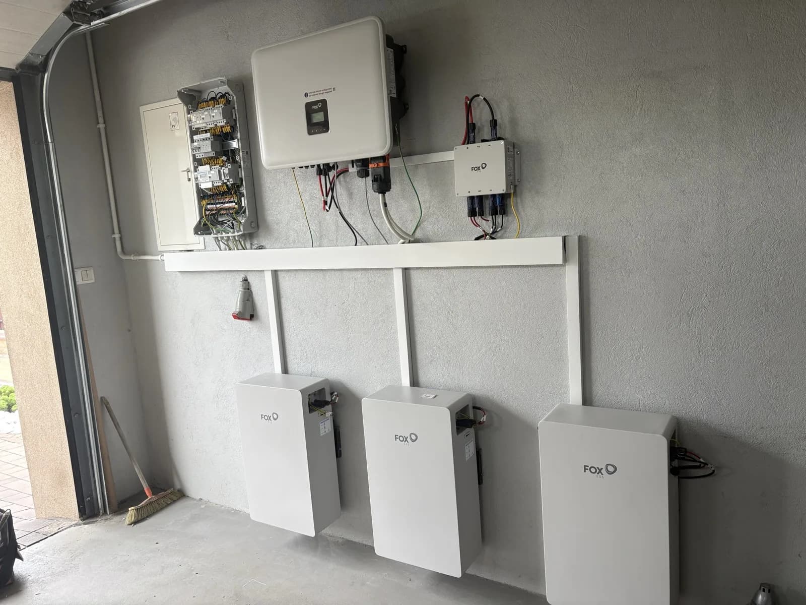 Magazyn energii FoxESS z falownikiem hybrydowym i rozdzielnicą, zamontowany w garażu domu jednorodzinnego. Typowa domowa instalacja, która mieści się w progu 30 kWh. Realizacja NEXBE.