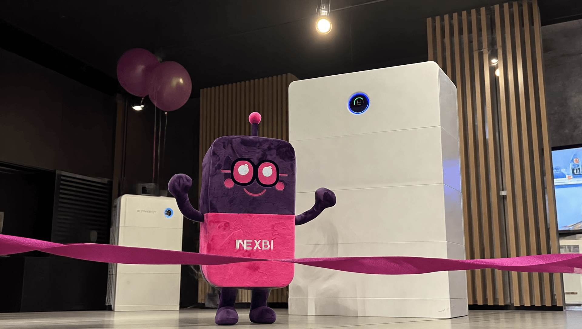 Maskotka NEXBI w showroomie NEXBE obok magazynów energii